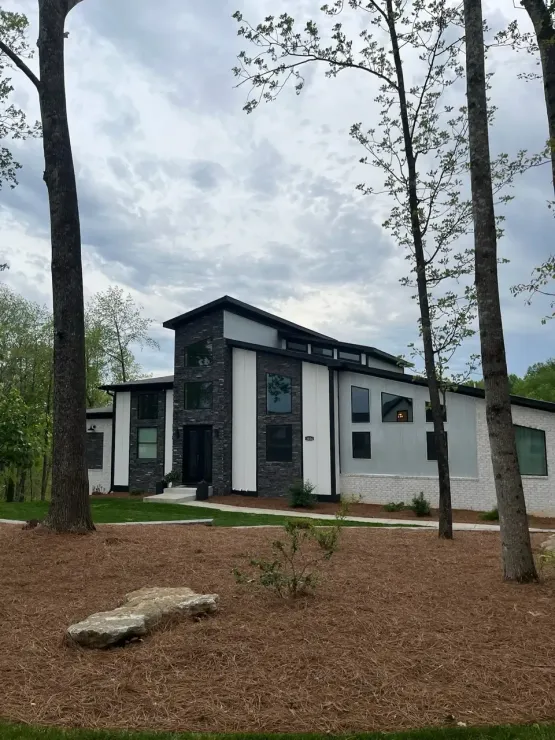 A house with a lot of windows is surrounded by trees