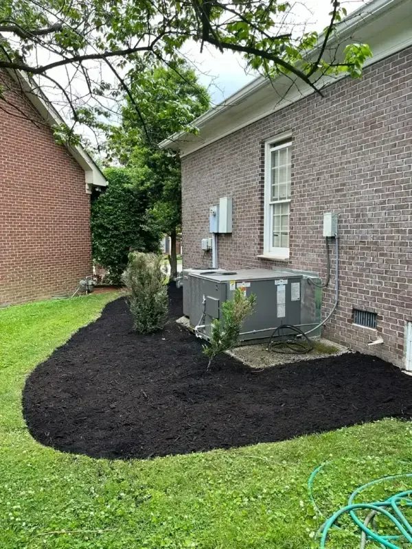 A brick house with a air conditioner in the backyard.