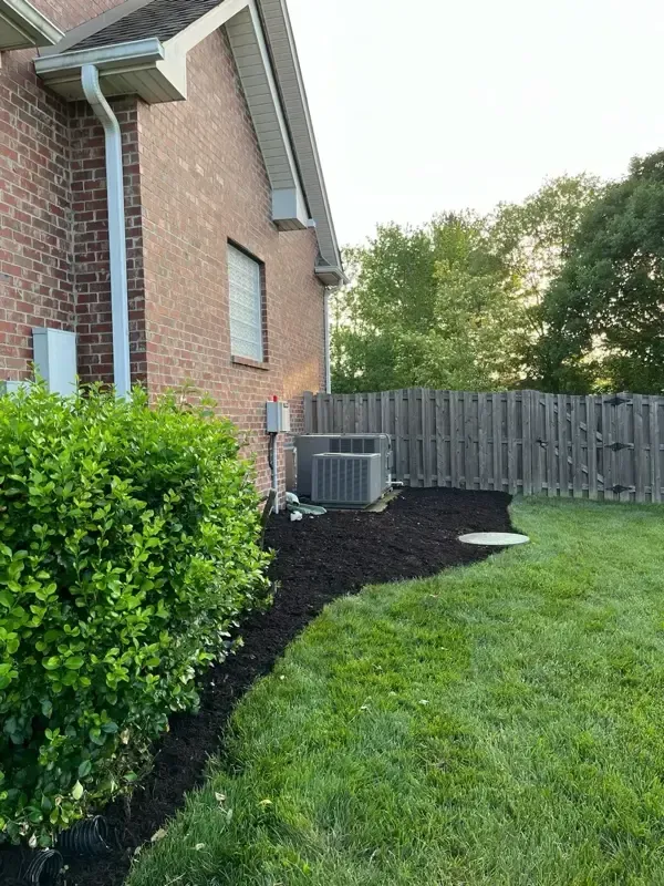 A brick house with a fence and a lawn in front of it.