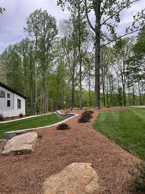 A white house is sitting in the middle of a lush green field surrounded by trees.
