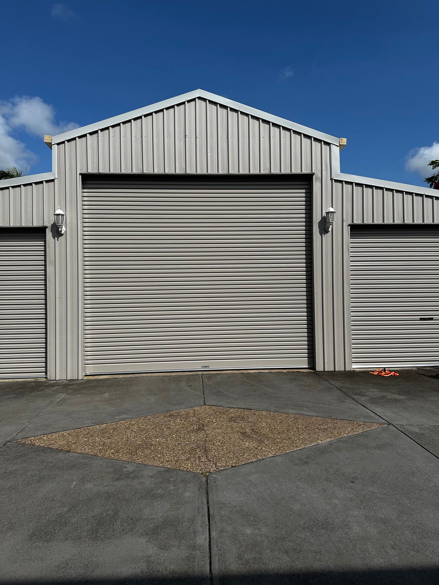Gray storage units with corrugated metal doors, under a blue sky.