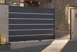 Sliding dark gray gate with silver accents in front of a house.