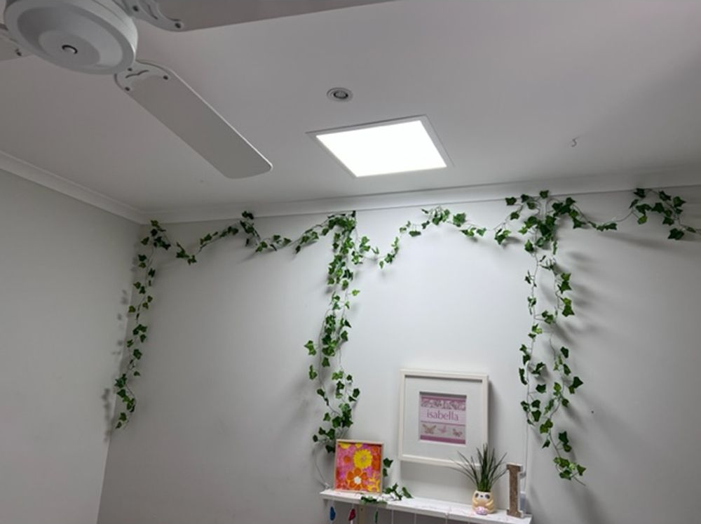 Wooden ceiling with skylights, illuminating a living room with brown leather sofa and light wooden floors.