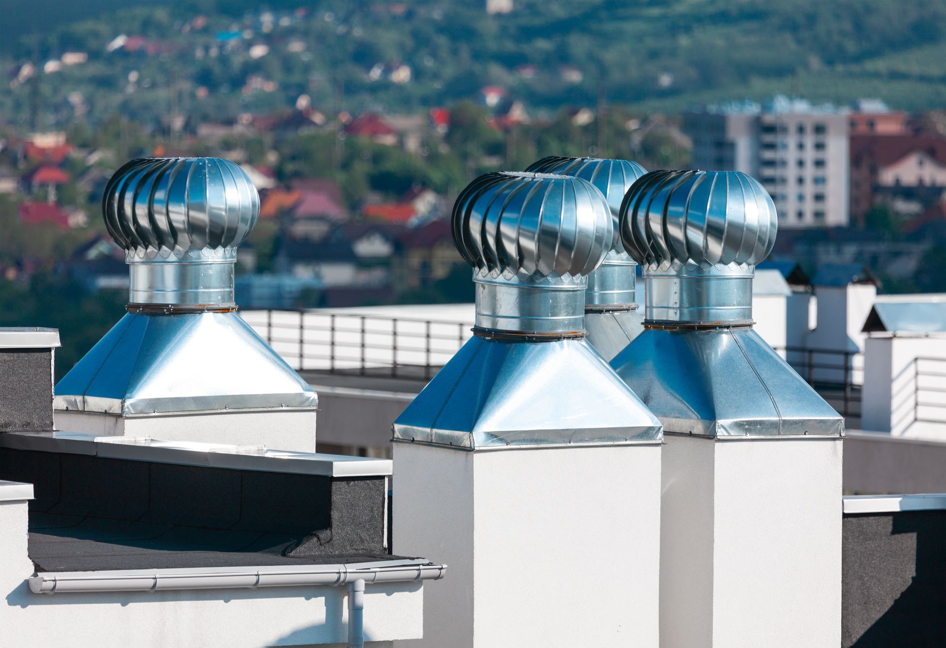 A silver roof vent on a metal roof against a clear blue sky.