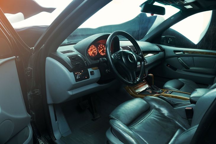Luxury car interior with black leather seats, illuminated dashboard, and open driver’s door