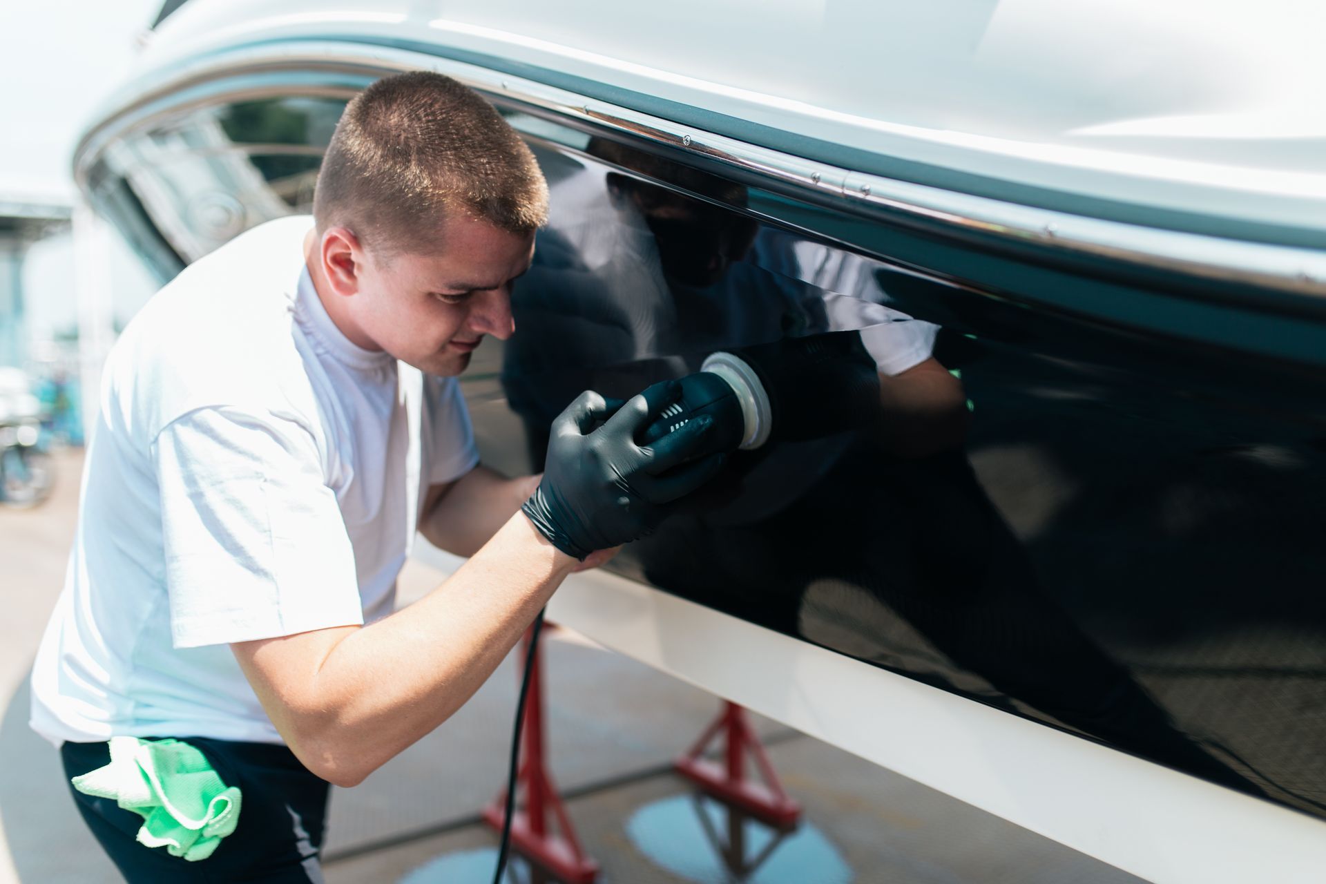 Technician polishing a boat hull with a power buffer in a workshop