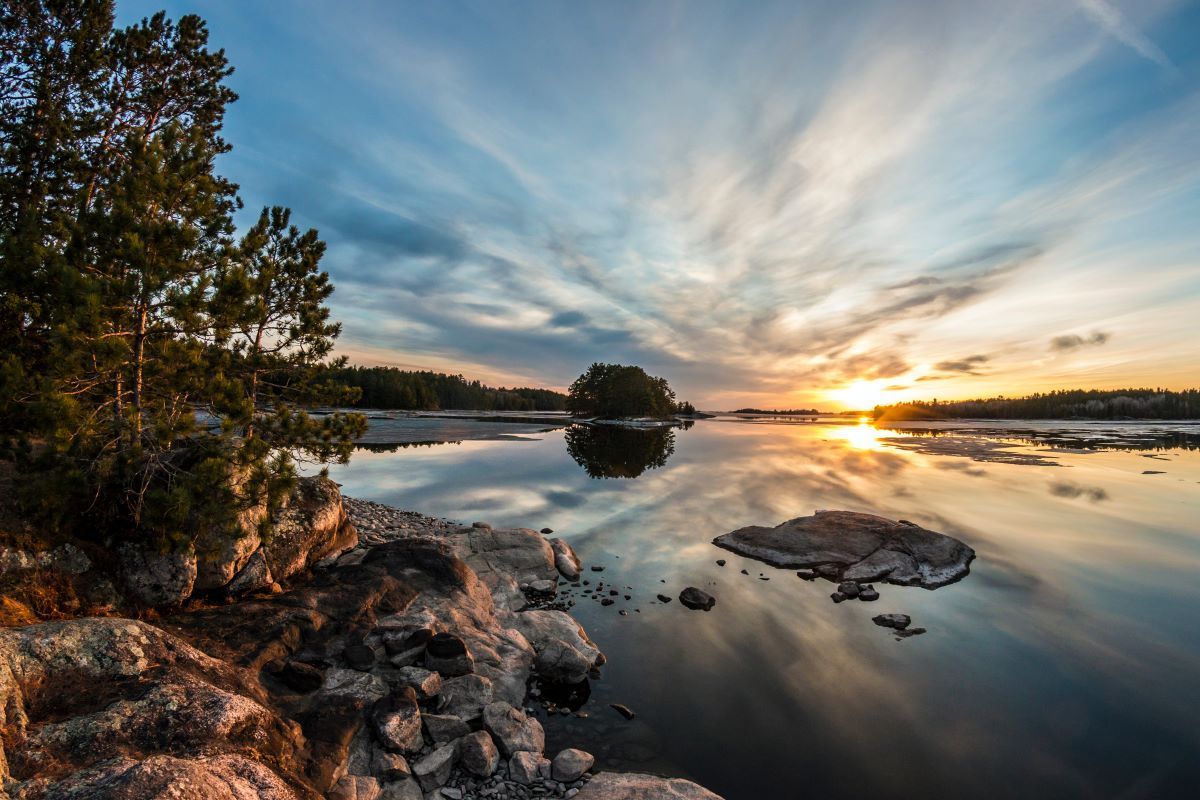 There is a small island in the middle of the lake at sunset.