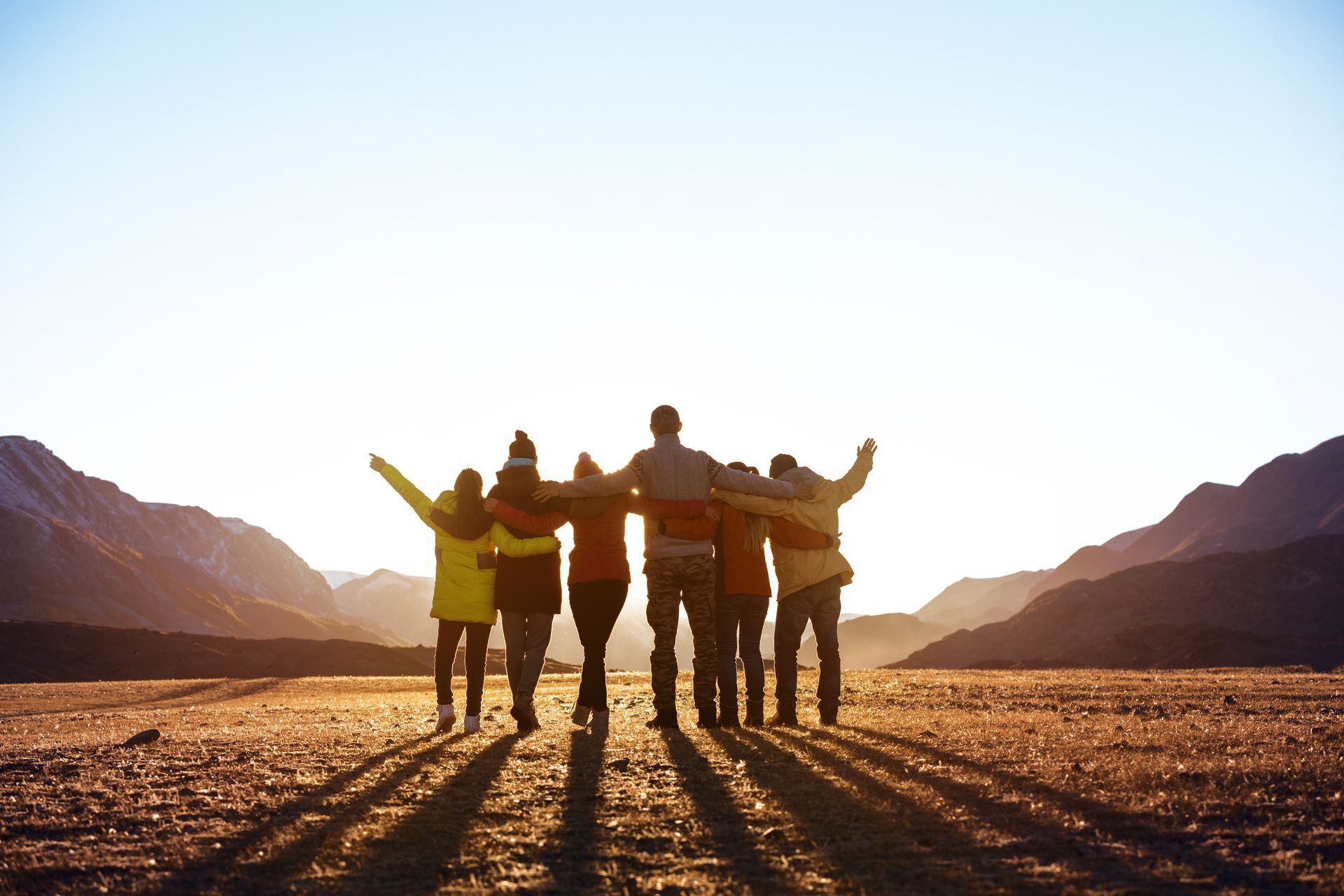 A group of people are standing next to each other with their arms around each other.