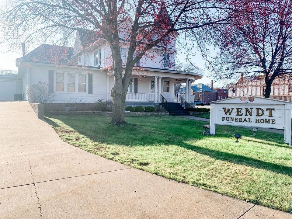 A white house with a sign in front of it that says wendt funeral home.