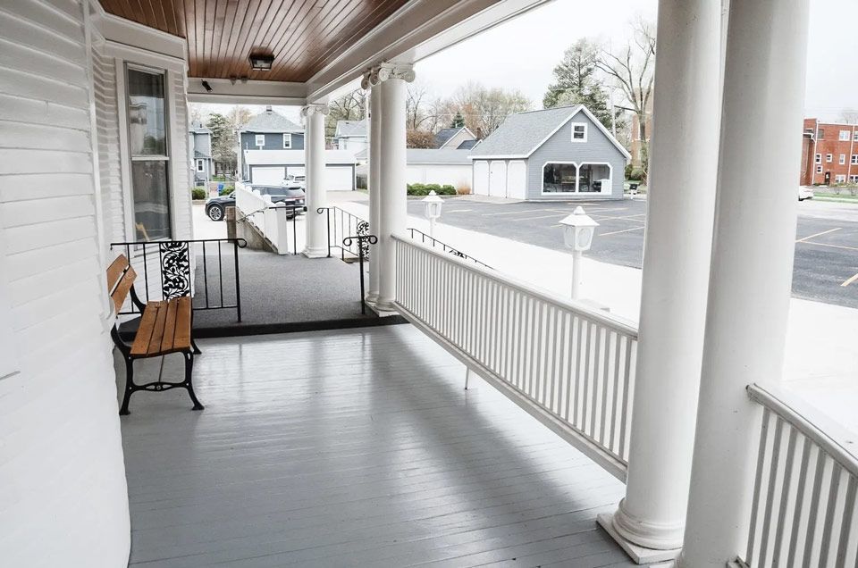 A porch with a wooden bench and a white railing