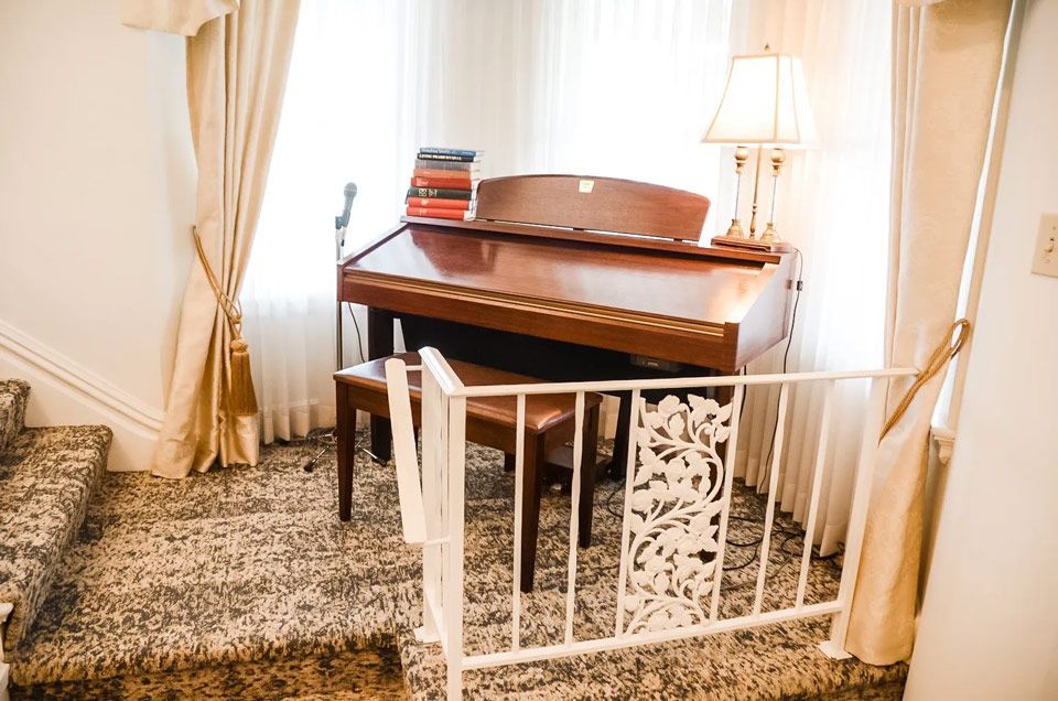 A piano is sitting in a room next to stairs.