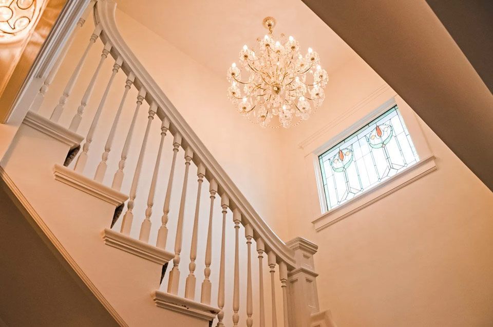 A staircase with a stained glass window and a chandelier hanging from the ceiling.