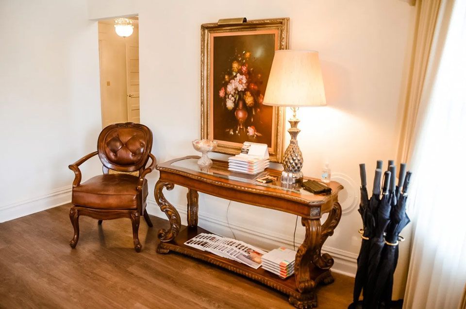 A living room with a table , chair , lamp and umbrellas.