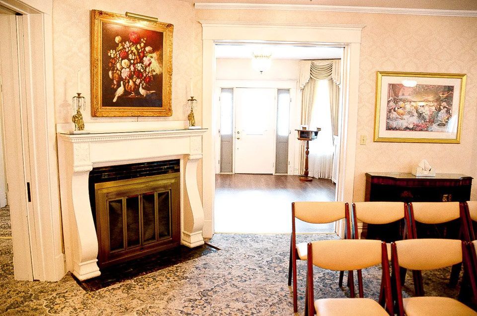 A room with a fireplace , chairs and a painting on the wall.