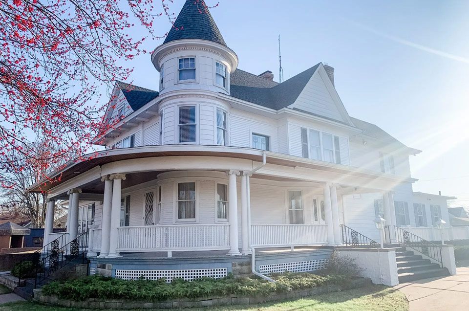A large white house with a tower on top of it and a large porch.