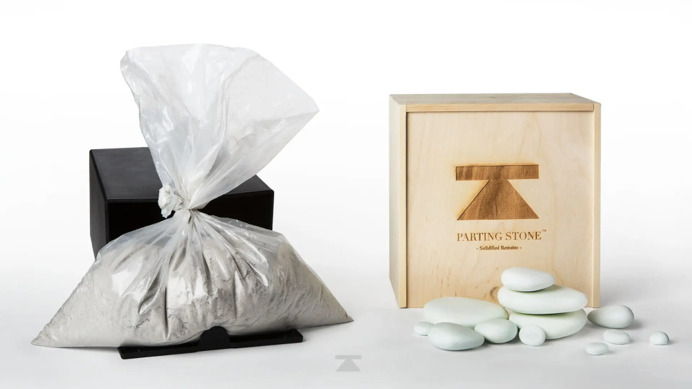 A bag of sand is sitting next to a box of rocks.