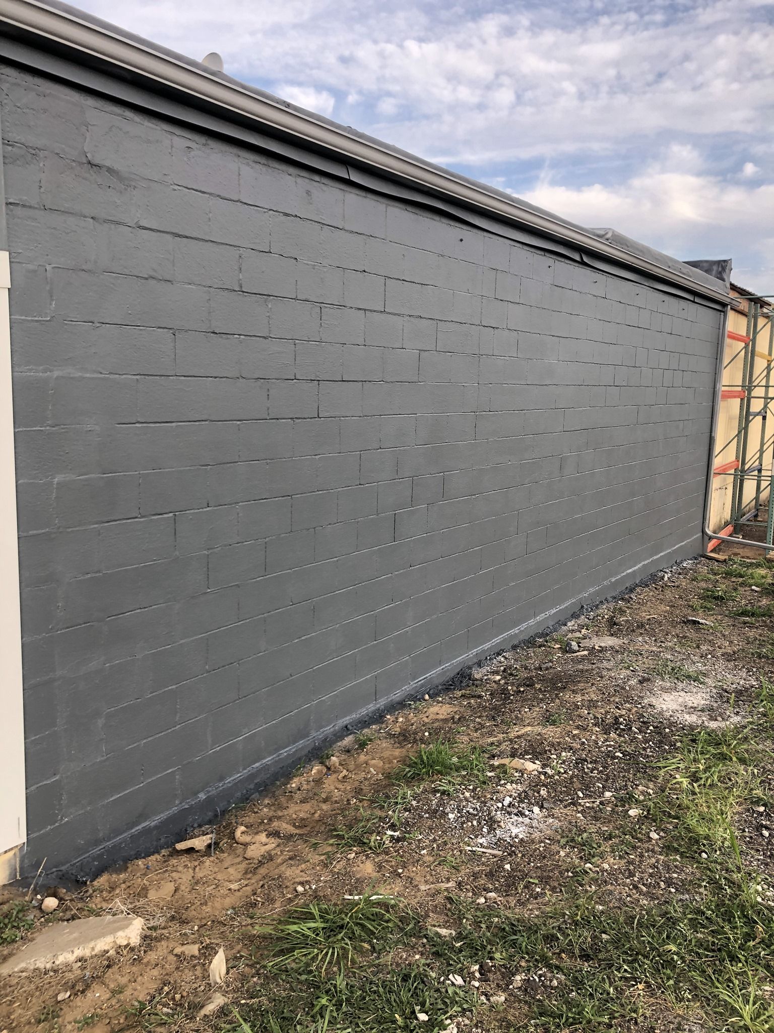 A large gray brick wall is sitting in the middle of a grassy field.