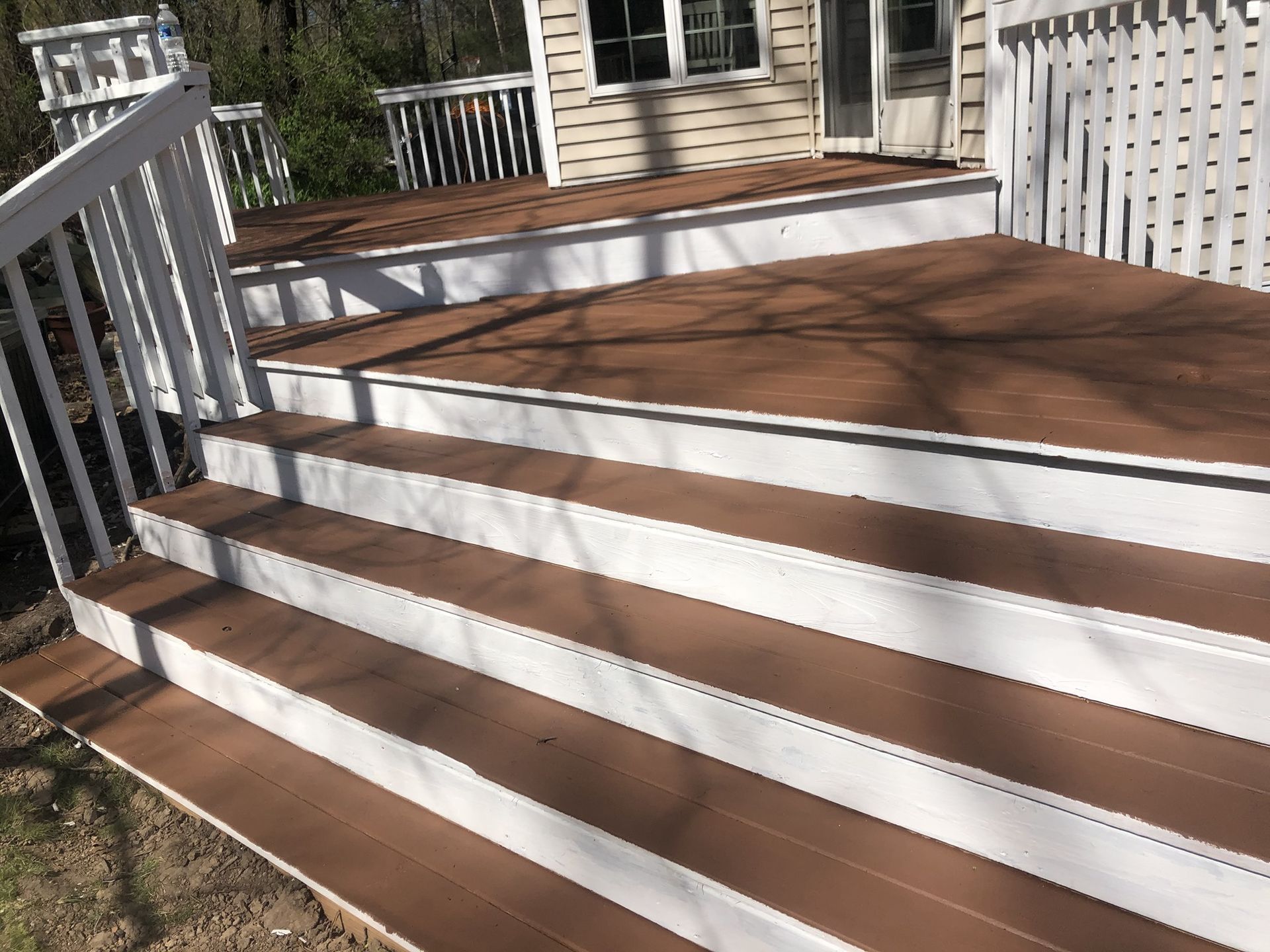 A wooden deck with white stairs and a white railing.