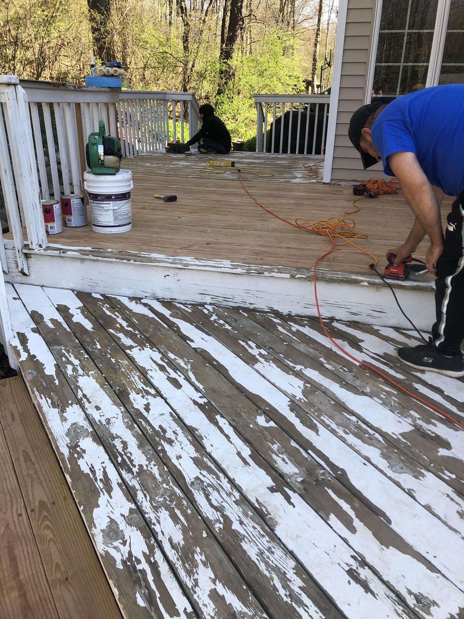 A man is painting a wooden deck with white paint.