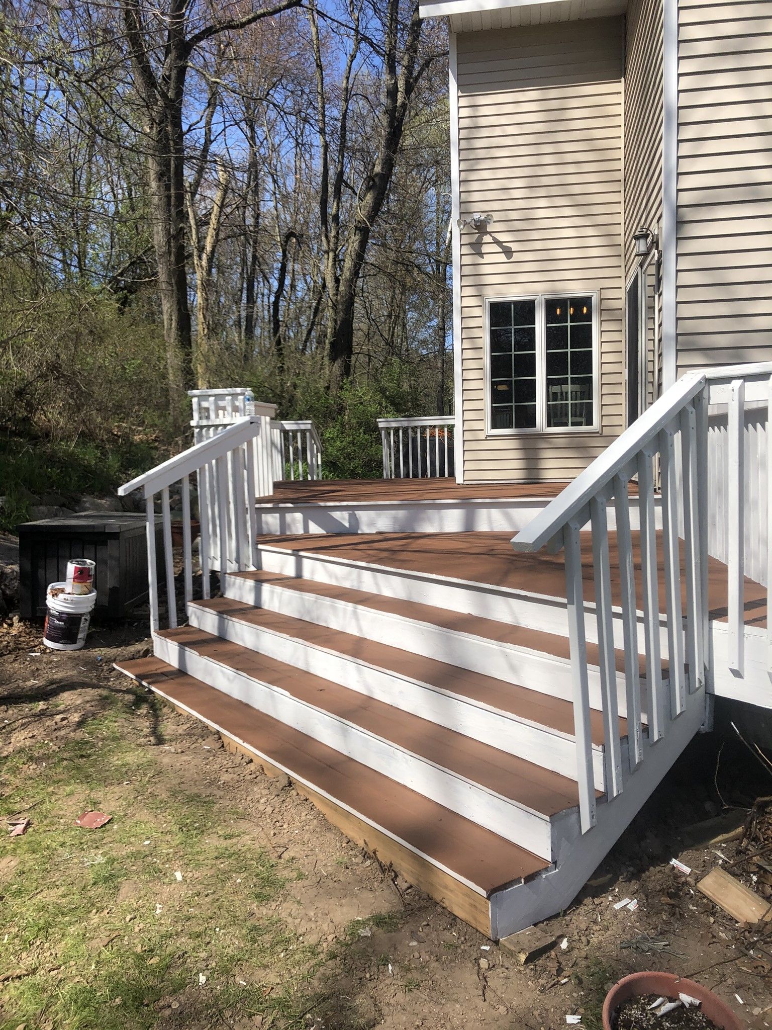 A deck with stairs and a white railing in front of a house.