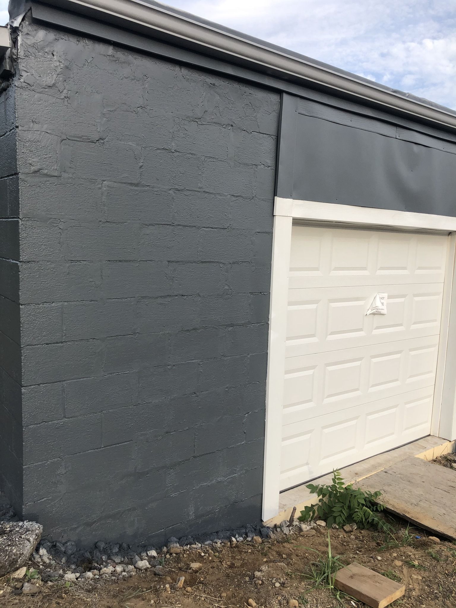 A black brick building with a white garage door.