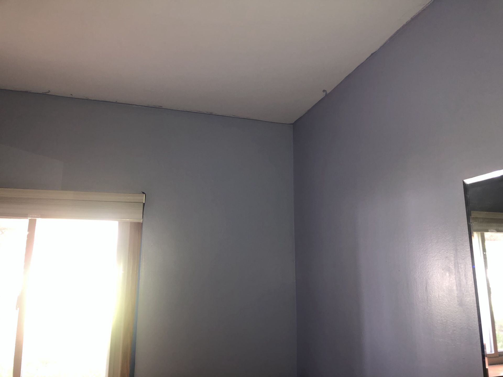 A room with a window and a mirror on the wall.