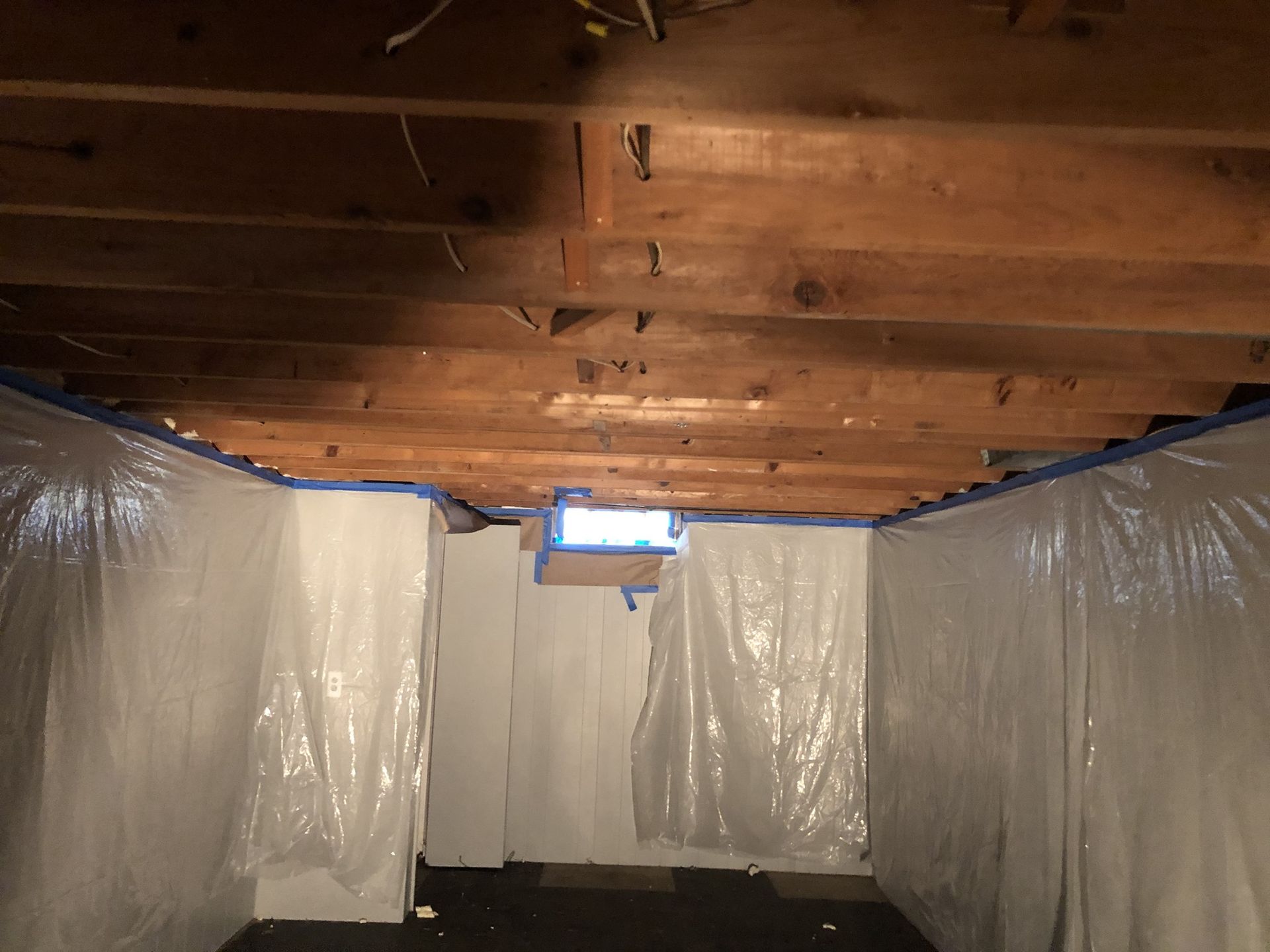 A basement with plastic covering the walls and ceiling.