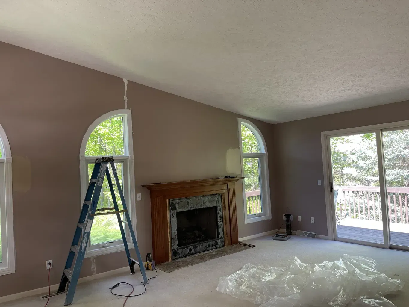 A living room with a fireplace and a ladder in it.