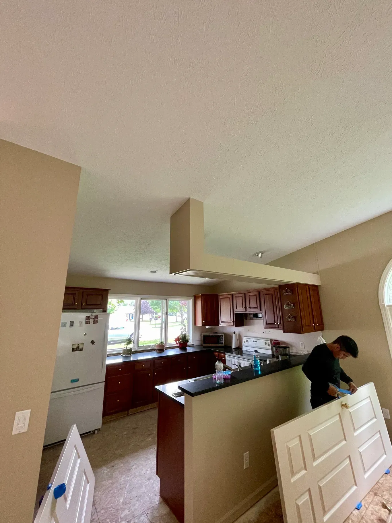 A man is working in a kitchen with a refrigerator.