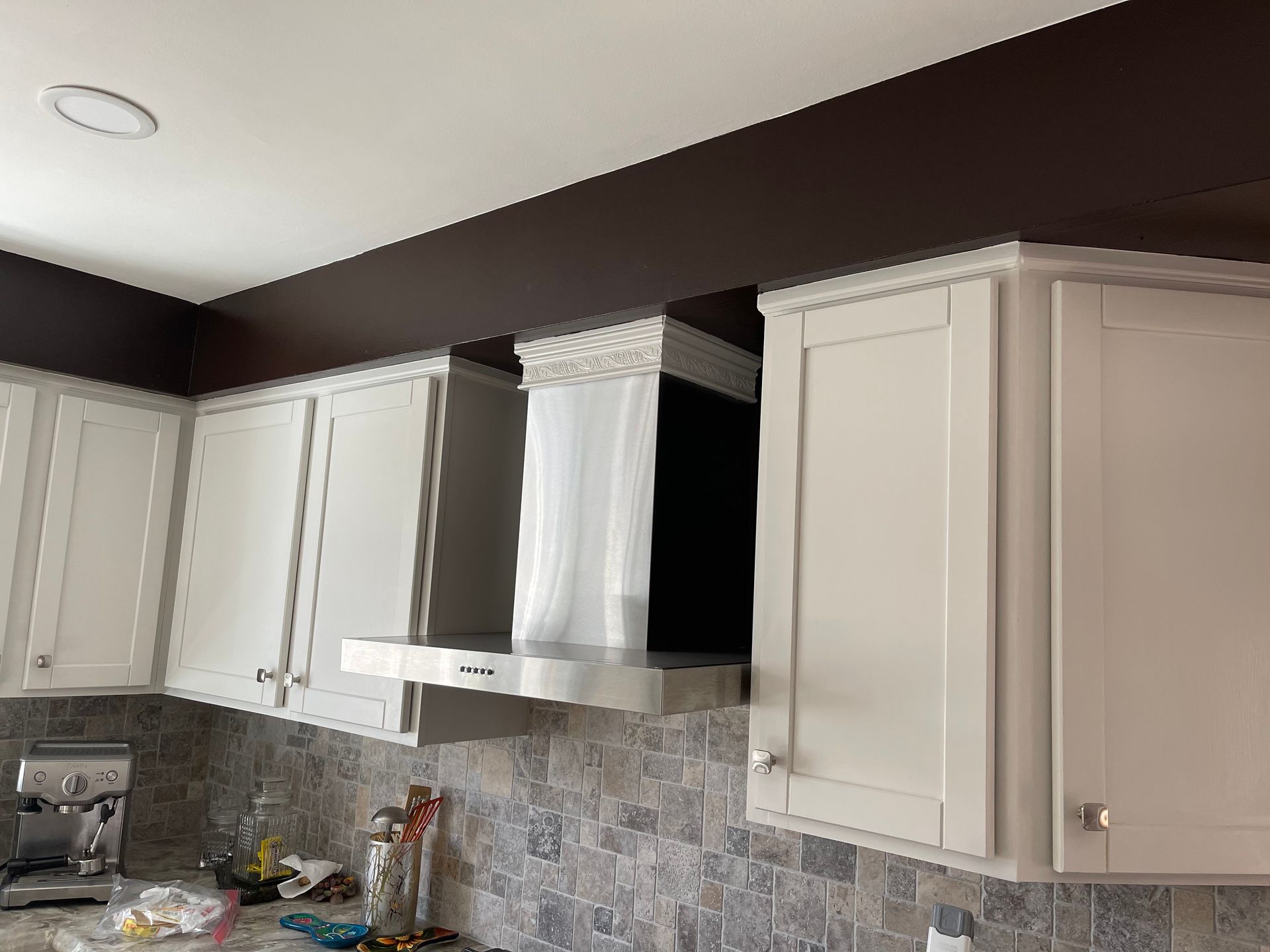 A kitchen with white cabinets and a stainless steel hood.
