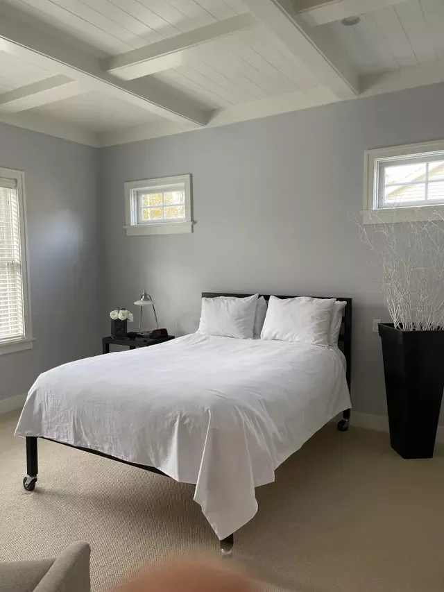 A bedroom with a bed and two windows