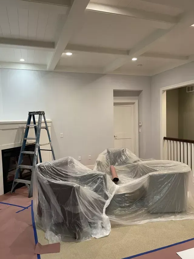 A living room with a couch and chairs wrapped in plastic.