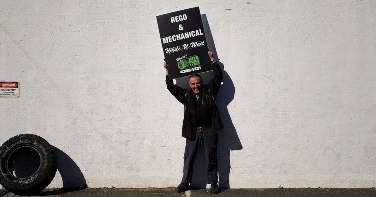 A man is holding a sign that says on it — Rite Price Tyres In Berkeley Vale, NSW