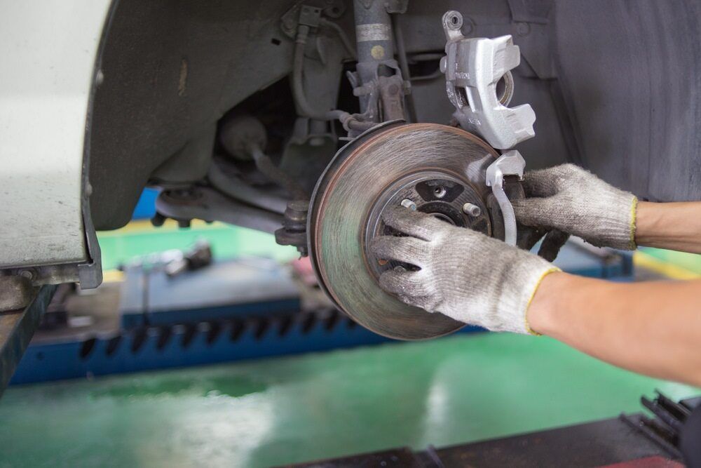 A Person is Fixing a Brake Disc on a Car in a Garage — Rite Price Tyres In The Entrance, NSW 