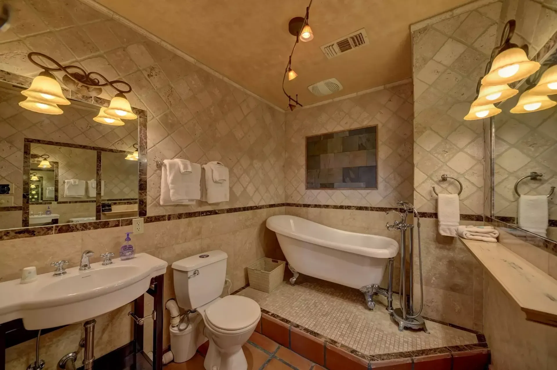Bathroom with white tub and sink, toilet, and decorative lighting.