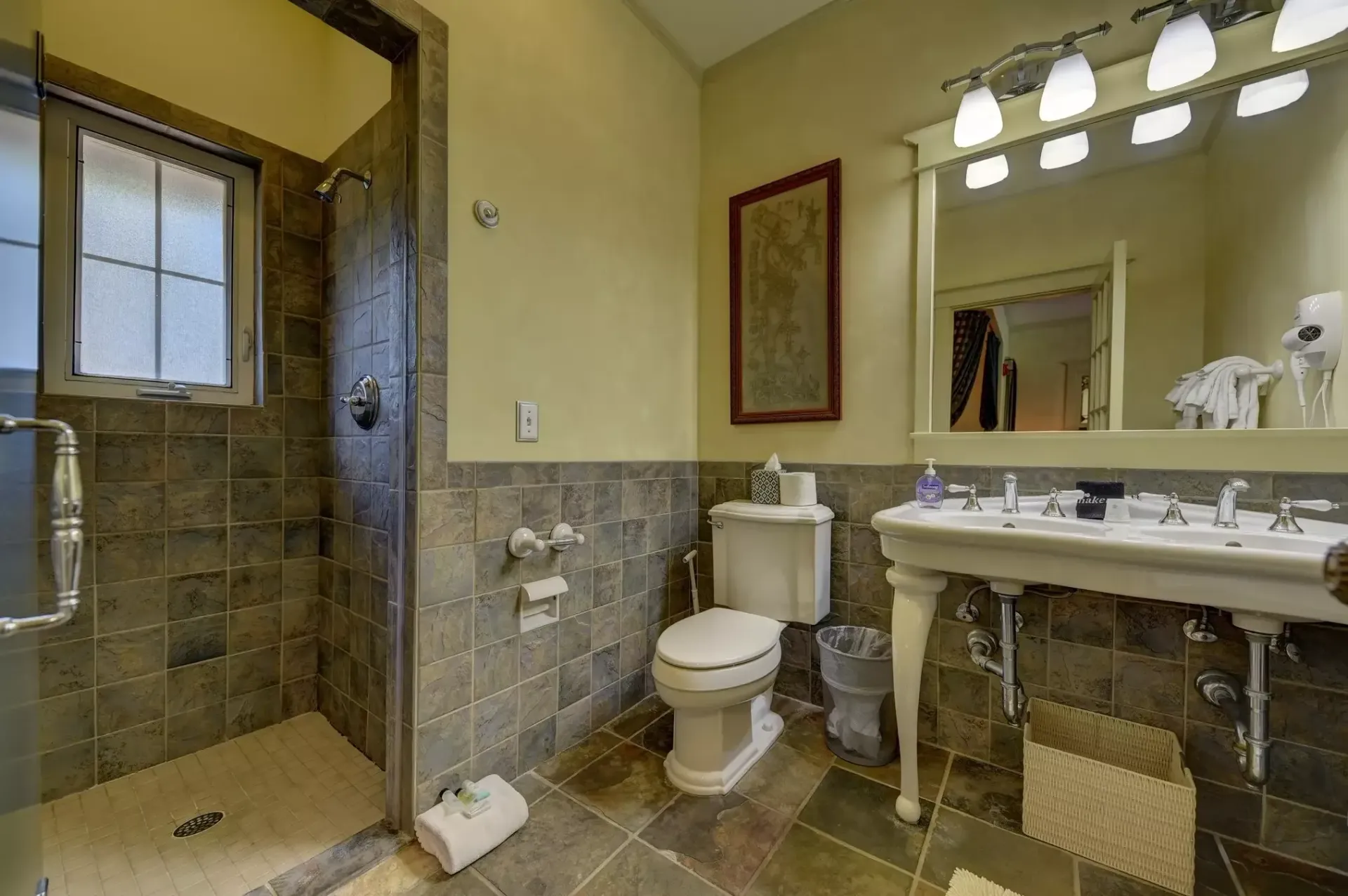 Bathroom with a walk-in shower, toilet, and vanity with a mirror. Slate tile walls and floor. Beige walls.