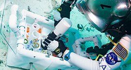 An astronaut is assembling a 3D printed part onto a machine