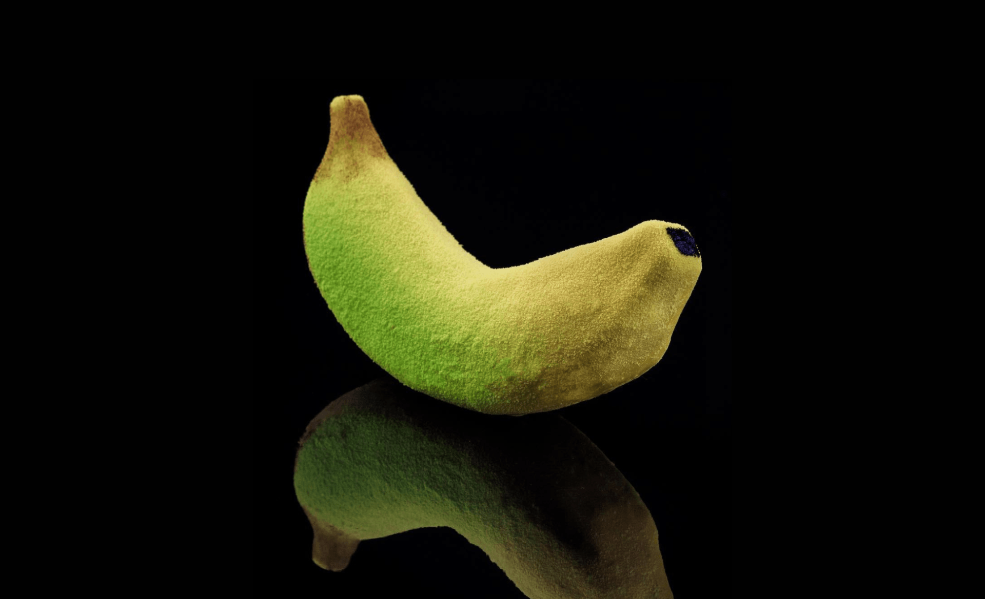 A yellowish banana in black blackground