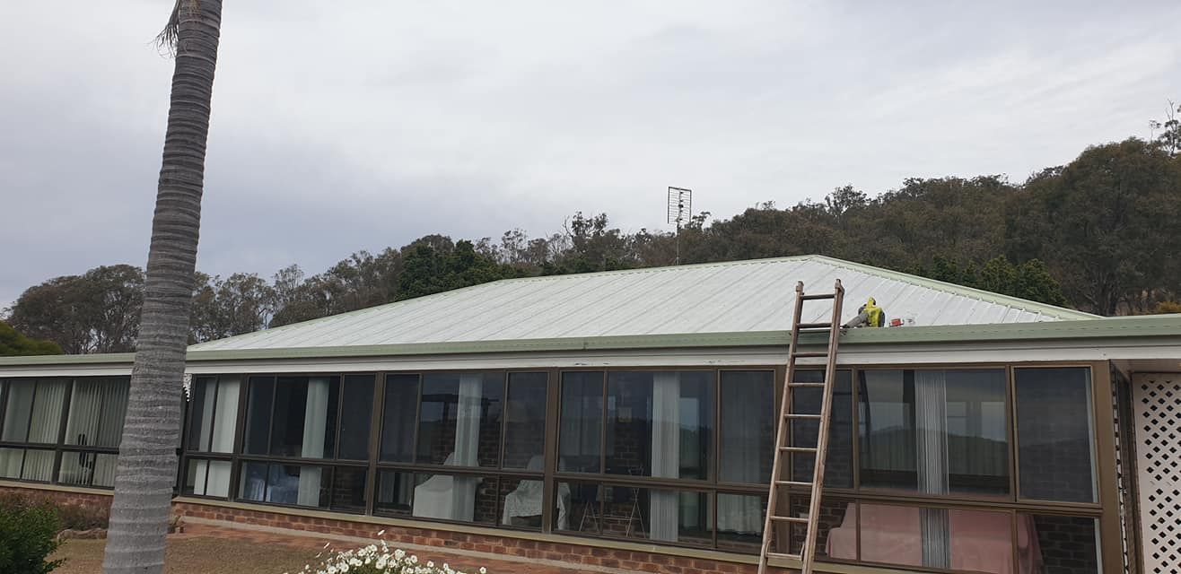Man is Painting the Roof of a House — Steve Oberhardt Roof Restorations & Repairs in Westbrook, QLD