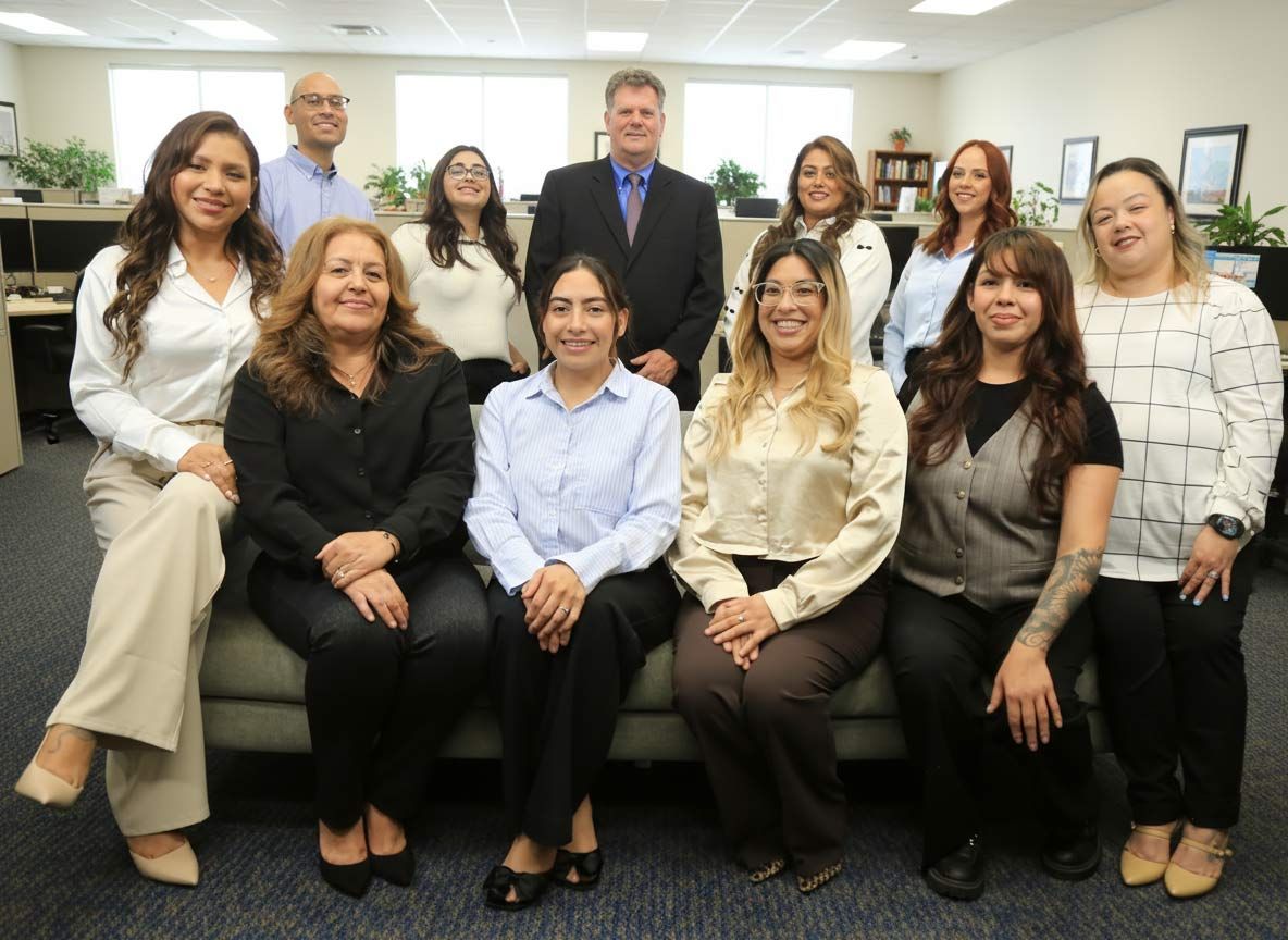 Group of people in an office setting, smiling and posing for a photo.