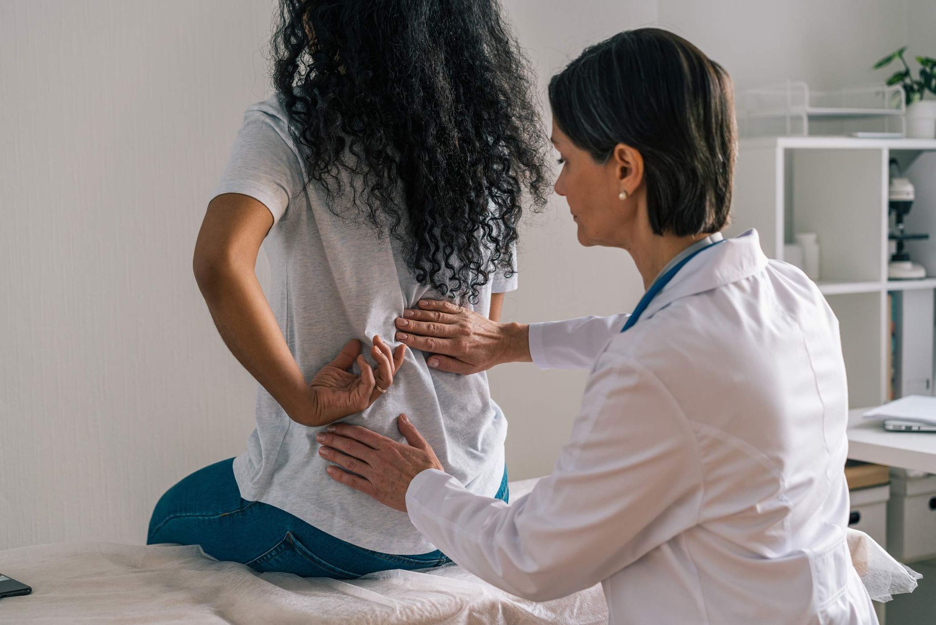 Doctor examining a patient's back pain in an office setting.