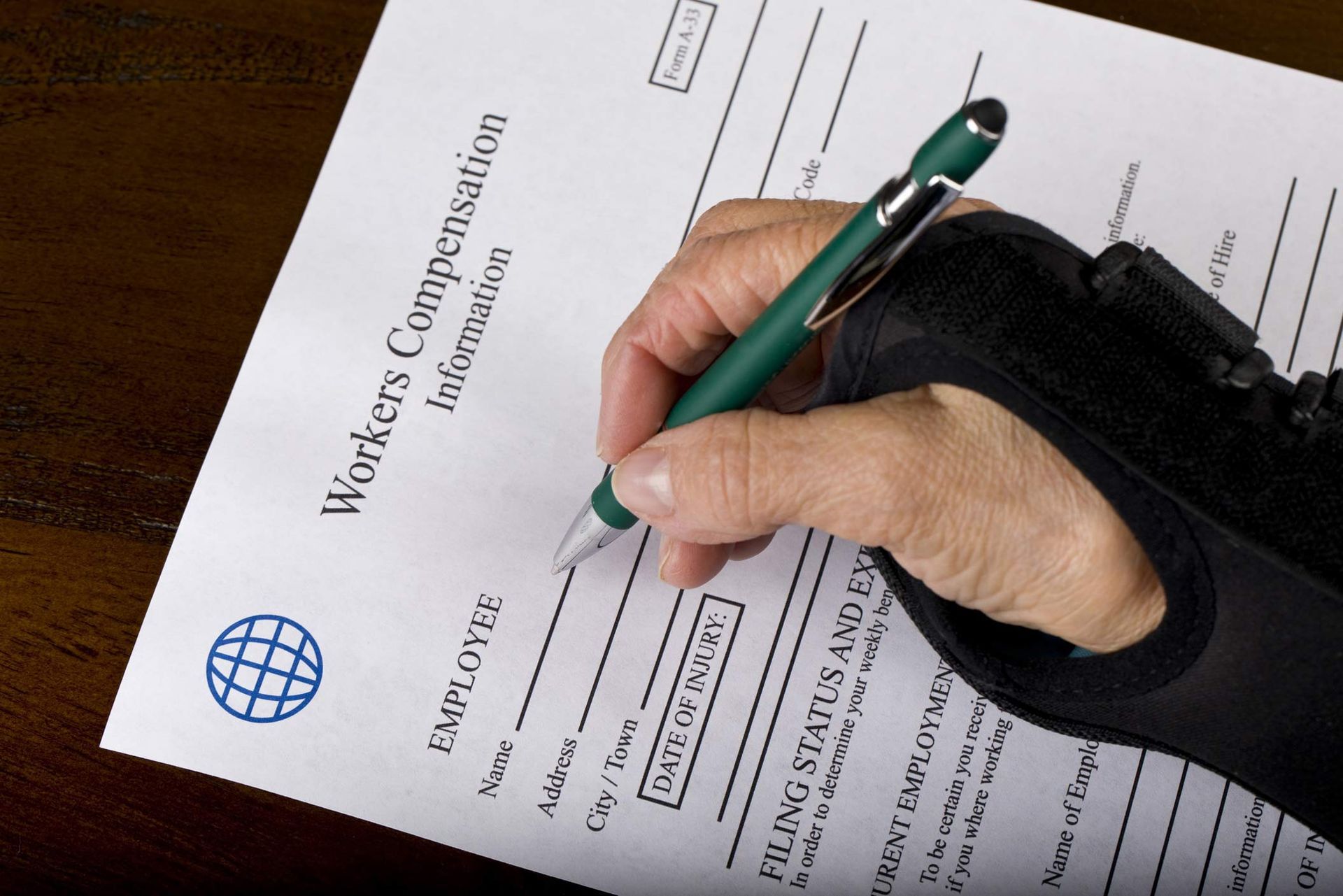 Hand with wrist brace writing on workers compensation form. Hand with wrist brace writing on workers compensation form.
