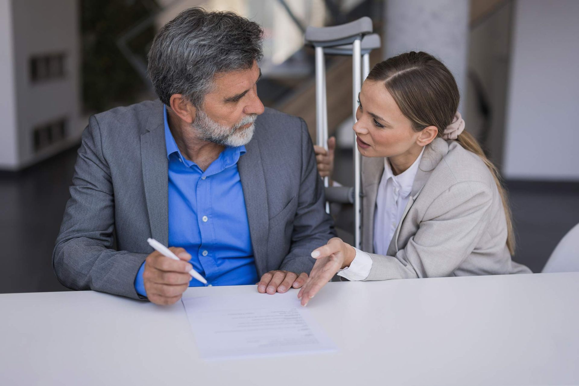 Man and woman review document at table; crutches behind them. Man and woman review document at table; crutches behind them.