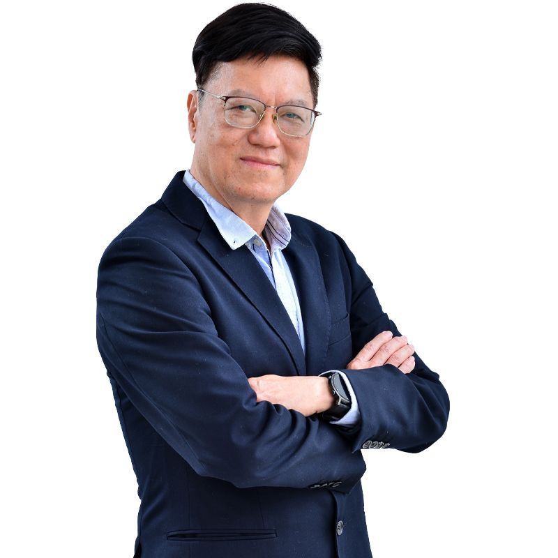 A man in a suit and glasses is standing with his arms crossed