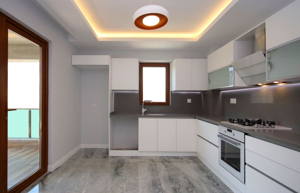 Modern White Kitchen With Grey Countertops, Built-in Appliances, and a Window — Morrison Cabinetry in Cedar Pocket, QLD