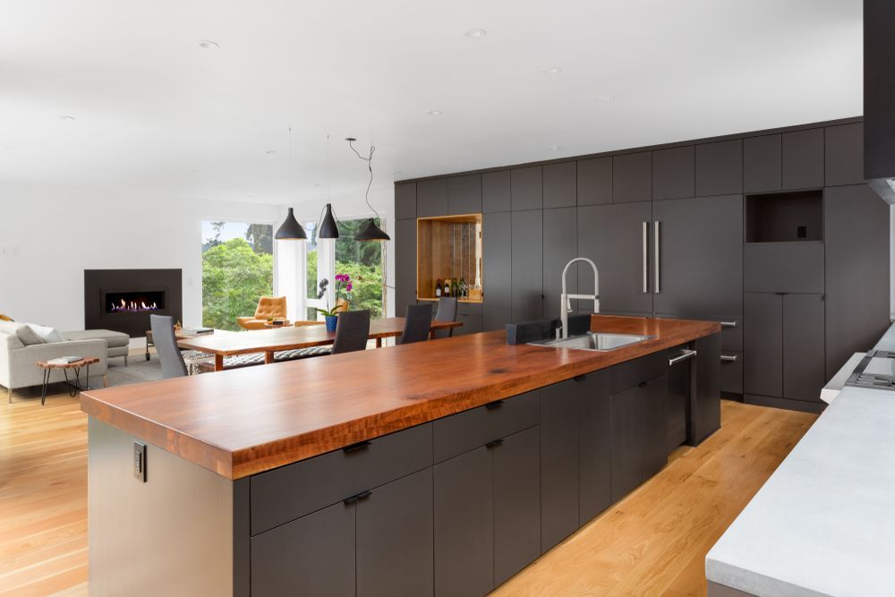 Modern kitchen with dark cabinetry, copper countertop island, and open-plan dining area — Morrison Cabinetry in Cooroy, QLD