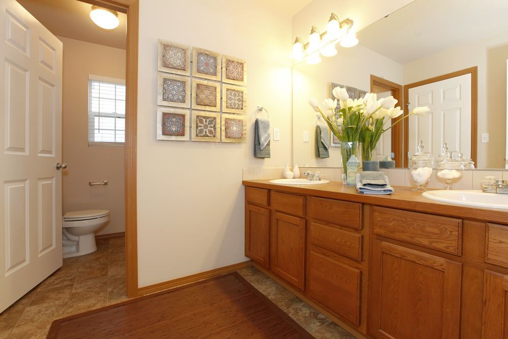 Bathroom With Brown Cabinets, White Sinks, and Floral Artwork — Morrison Cabinetry in Noosa, QLD