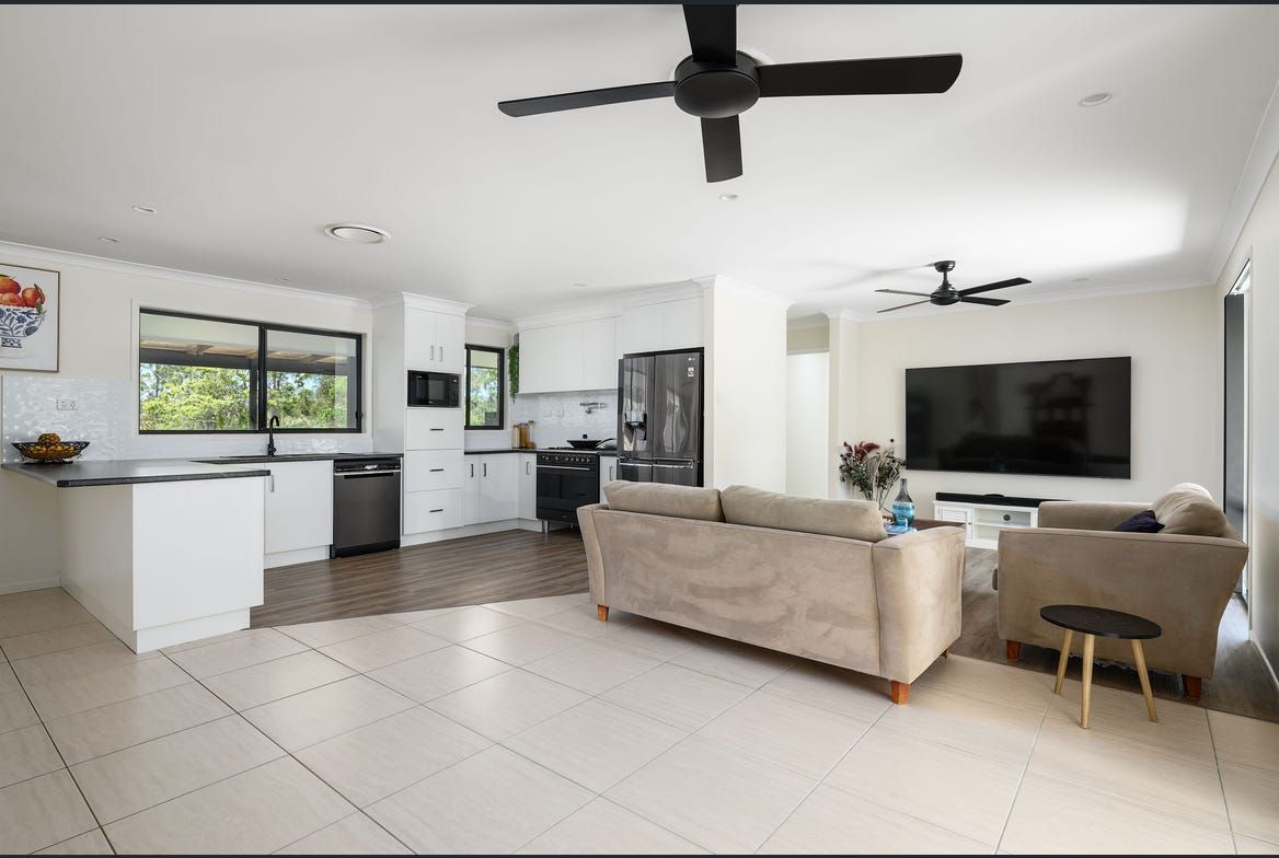 Open-plan living space with kitchen, lounge area, and white tile flooring — Morrison Cabinetry in Sunshine Coast, QLD