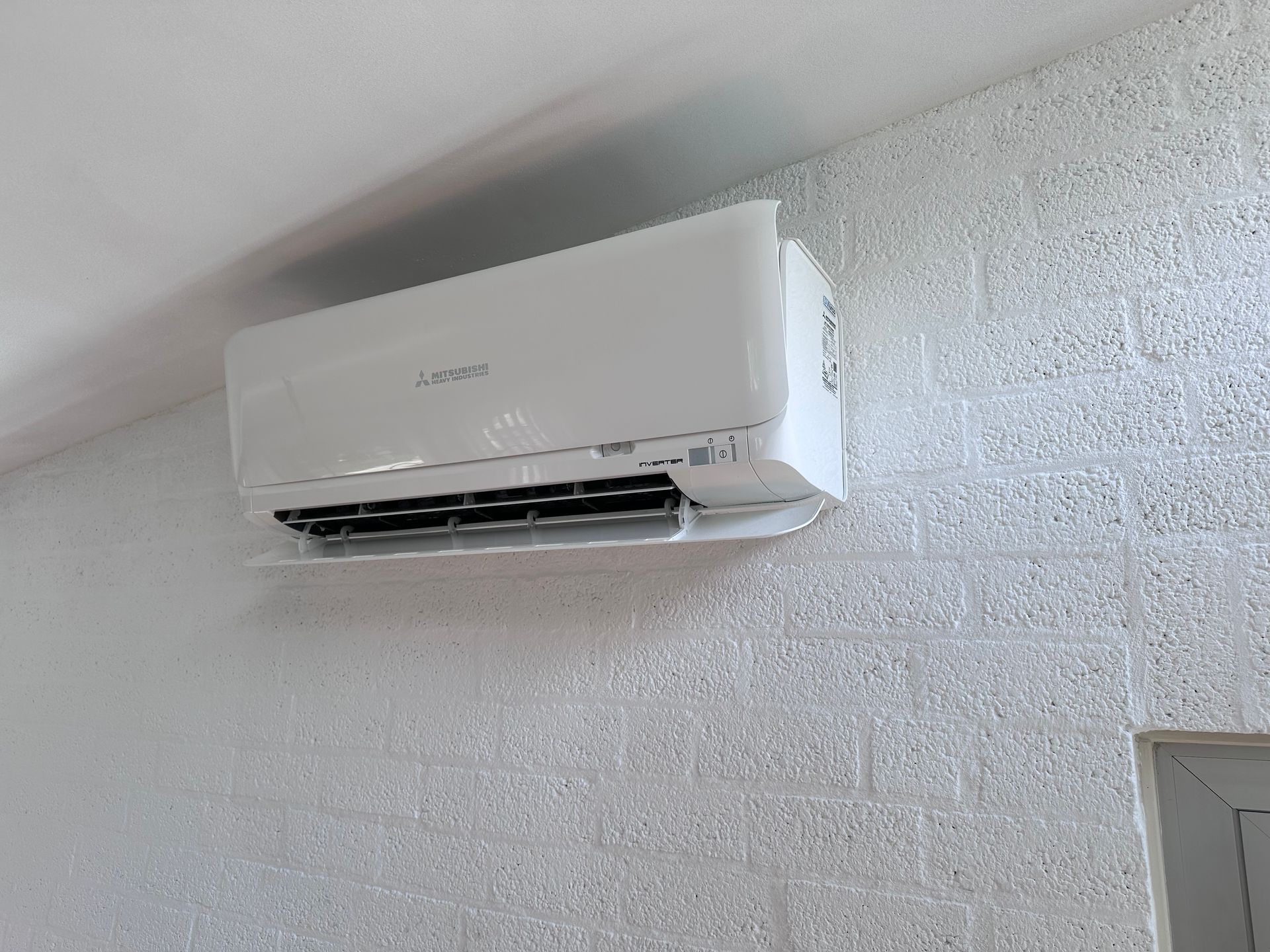 Een witte airconditioner hangt aan een witte muur.