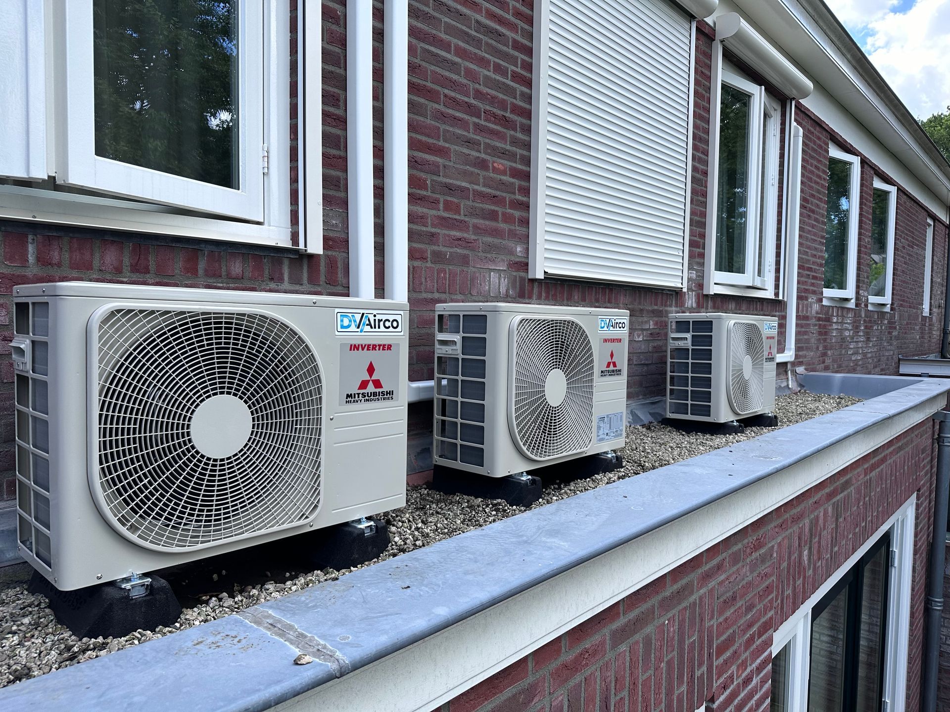 Een rij airconditioners staat op de zijkant van een bakstenen gebouw.